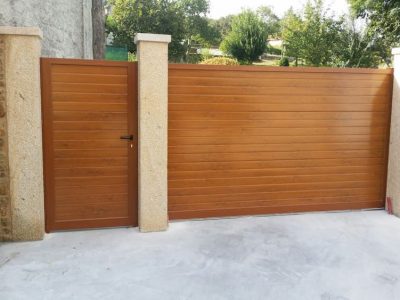 entrada a una casa, destacan una puerta de madera para usuarios y una con el mismo estilo pero mucho más grande para que pasen coches